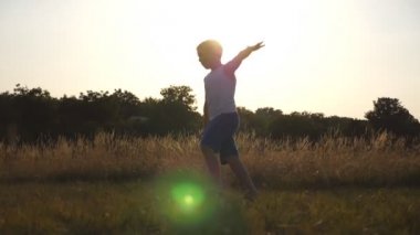 Genç çocukla güneşli günde yeşil çim alan, çalışan uçak eller olarak ortaya çıkar. Çim açık koşu çocuk. Mutlu erkek çocuk yaz çayır üzerinde doğada eğleniyor. Ağır çekim yakın çekim