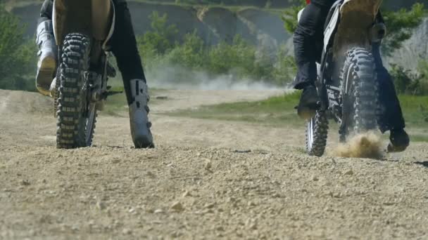 Twee motorfiets starten na elkaar. Bezaaid motorcross wiel begint te draaien, schoppen van vuil en stof. Slow motion dicht omhoog terug achteraanzicht — Stockvideo