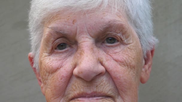 悲しい光景でおばあさんの肖像画。カメラに探している高齢者の女性のしわのある顔。おばあちゃんの悲しみの表情。成熟した女性の視線を閉じる — ストック動画