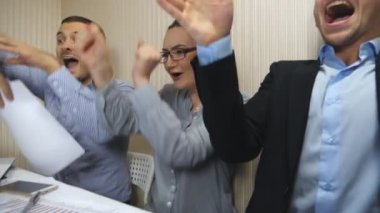 Genç iş adamları başarıyı kutluyor, belgeleri kusuyor ve neşeli duygular gösteriyorlar. Ofis çalışanları sıkı çalışmadan sonra başarıya sevinirler. Modern ofiste çalışan yaratıcı ekip. Yavaş çekim