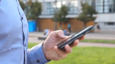 Elini tutarak ve smartphone dokunmadan genç işadamı kapatın. Kentsel Caddesi üzerinde duran ve telefon haber tarama tanınmayan adam. Adam iş için Gadget'ı kullanma. Ağır çekim Dolly vurdu