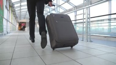 Bacaklar terminal salonunda çalışan ve bavul tekerlekleri çekerek başarılı iş adamı. Kamera takip onun Bagaj ile genç adam için uçuş için geç oldu. Adam acele iş gezisi için. Yavaş mo yakın çekim