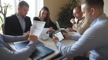 Modern ofiste masada oturan ve yeni bir proje üzerinde çalışan bir grup genç iş adamı. Meslektaşlar çalışırken belgeleri dikkatle incelerler. Ofis çalışanları iş geliştirmekle meşgul. Yavaş çekim