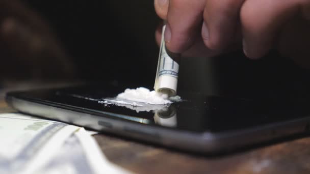 Чоловічий наркоман нюхає кокаїнову лінію з екрану телефону через скручений доларовий рахунок. Чоловік винюхує білий порошок і кидає загорнуту банкноту, насолоджуючись наркотиками. Розмитий фон. Повільний mo Крупним планом — стокове відео