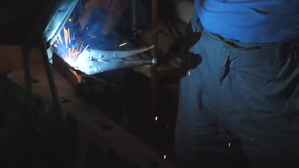 修理工やメカニック労働者の男性の手は、ワークショップで溶接機を使用して、古い車の金属部品を溶接します。点滅し、火花がガレージで暗いで溶接作業から飛びます。クローズアップスローモーションドリーショット — ストック動画