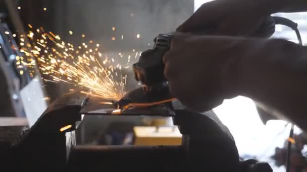 Close up arms of male welder sawing metal with a circular saw in garage. Male hands of professional repairman or mechanic worker cutting steel using electric grinding wheel in workshop. Dolly shot — Stock Video