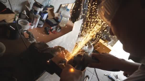 Schweißer, der Stahl mit elektrischer Schleifscheibe und Schutzbrille in der Garage schneidet. Handwerker oder Mechaniker sägen in der Werkstatt Metall mit der Kreissäge. Zeitlupe von oben — Stockvideo