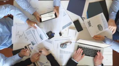 Ofiste kurumsal proje için strateji planlama iş adamlarının üst görünüm erkek ve kadın elleri. İş ekibi masada oturuyor ve finansal grafikleri kontrol ediyor. Masa başında belgeleri inceleyen iş arkadaşları