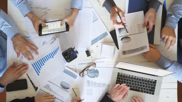 Top view male and female hands of business people planning strategy for corporate project in office. Business team checks financial graphs at desk. Colleagues sitting at table and examining documents — Stock Video