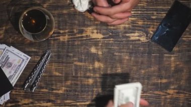 Masaya döviz demeti koyan işadamının üst görünümü. Uyuşturucu satıcısının erkek kolları para alıyor, müşteriye kokain veriyor ve birbirleri için el sıkışıyor. Yavaş çekim