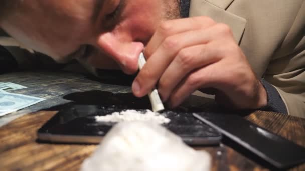 Close-up van de jonge drugdealer snuiven drug door gerold 100 dollar Bill van telefoon scherm. Mannelijke verslaafde doorgegeven na cocaïne overdosis op tafel. Verslaving en drugsmisbruik concept — Stockvideo