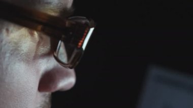 Gece geç saatlerde dizüstü bilgisayarda çalışan ekran ışıkları yansıması ile gözlük girişimcierkek gözleri kapatın. Ofiste not defteri kullanarak monitöre bakan genç işadamıprofili