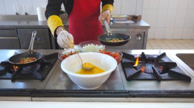 Tanınmayan şef restoranın modern mutfağında lezzetli vejetaryen yemek pişirir. Erkek aşçı tavada malzemeler ekleyerek. İşyerinde çalışan profesyonel şef. Pişirme sürecinin görünümü. Yavaş mo