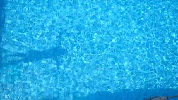 プールに飛び込み、透明な水をはねかねる若者のトップビュー。晴れた日に流域で水中を泳いでいる認識できない男。夏休みにリラックスした少年。スローモーションクローズアップ — ストック動画
