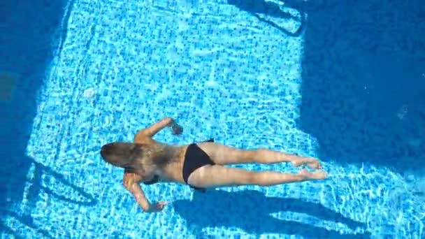 Donna irriconoscibile in bikini nero che nuota sott'acqua ed emerge in superficie. Ragazza sexy rilassante durante le vacanze estive rinfrescante nel bacino dell'hotel. Concetto di viaggio o vacanza. Lento mo Vista dall'alto — Video Stock