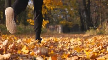 Sonbahar parkta çalışan tanınmayan sporcu, Kuru akçaağaç yaprakları üzerinde adım. Renkli düşmüş yaprakları üzerinde erkek Runner jogging. Doğada genç atlet eğitimi. Sağlıklı yaşam konsepti. Arka görünüm
