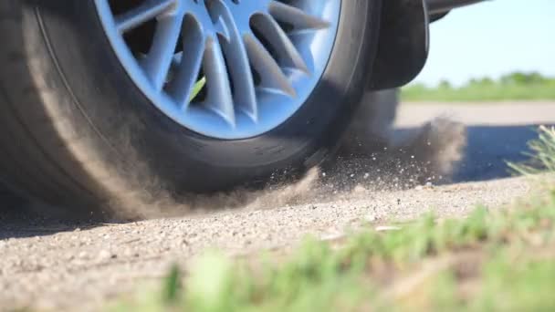 Rueda del coche se deslizan en un camino de tierra durante el inicio del movimiento. Pequeñas piedras y la suciedad es volar fuera de debajo de la llanta de un auto. Vehículo que comienza rápidamente el movimiento.Concepto de burnout. Cámara lenta Primer plano — Vídeos de Stock