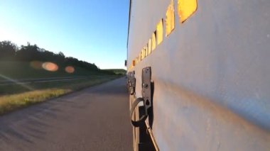 Otoyolda kamyon sürüyor. Kamyon kırsaldan geçiyor. Traktör römorkundan asfalt yola giden araba trafiğine bakış açısı. Taşımacılık ve ticari araç kavramı. Zaman Süreleri