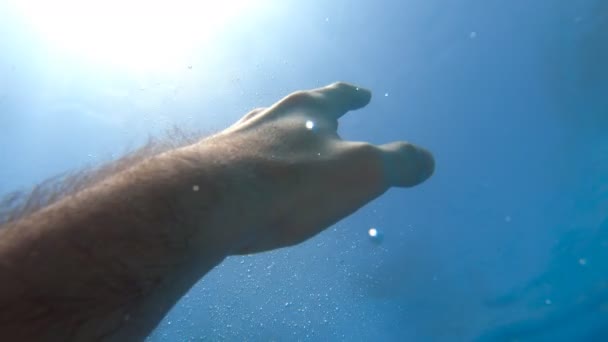 Чоловіча рука тягнеться від води до сонячних променів. Рука просить допомоги і намагається дістатися до сонця. Точка зору людини, що тоне в морі або океані і пливе на поверхню. Повільний рух POV — стокове відео