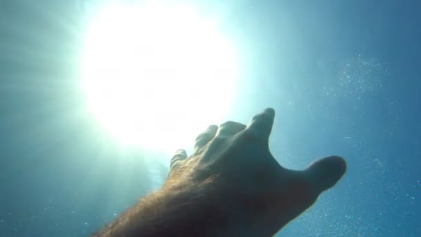 Manlig hand sträcker sig från under vattnet till solstrålar. Arm ber om hjälp och försöker nå solen. Synvinkeln att människan drunknar i havet och flyter upp till ytan. Långsamma rörelser POV — Stockvideo