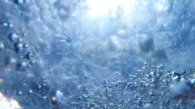 Hava kabarcıkları su yüzeyine kadar yüzen. Turkuaz saf denizde yükselen çok sayıda küçük hava kabarcıkları. Güneşli yaz gününde kristal berraklığında okyanus suyuna nüfuz eden ılık güneş ışığı. Yavaş çekim Yakın çekim