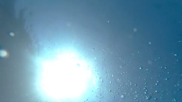 Bolhas de ar flutuando até a superfície da água. Numerosas pequenas bolhas de ar subindo em mar puro turquesa. Luz do sol quente penetrando água cristalina do oceano no dia ensolarado de verão. Lento movimento Fechar — Vídeo de Stock