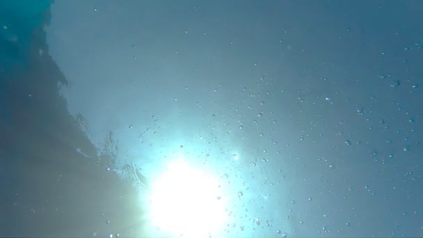 A vízfelületre Felúszó légbuborékok. Számos kis légbuborék emelkedik ki a türkiz tiszta tengerben. Meleg napsütésben behatoló kristálytiszta óceán víz napsütéses nyári napon. Lassú mozgás közelről — Stock videók