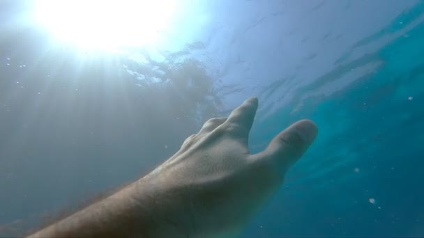 Bras demandant de l'aide et essayant d'atteindre le soleil. Point de vue de l'homme se noyant dans la mer ou l'océan et flottant à la surface. La main masculine s'étend de sous l'eau aux rayons du soleil. Mouvement lent POV — Video