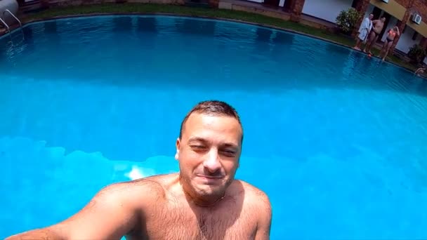 Young man jumping in pool with action camera in hand. Caucasian guy swimming under water in basin at sunny day. Boy relaxing during summer vacation. Underwater footage. Slow motion Close up — Stock Video