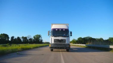 Yaz günü mal taşıma karayolu üzerinde sürüş kargo römork ile kamyon ön görünümü. Beyaz kamyon arka planda güzel manzara ile kırsal üzerinden sürme. Yavaş mo Ön görünüm Kapat