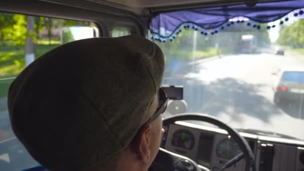 Zicht op onherkenbaar vrachtwagenchauffeur binnen cabine rijden op City Road en genieten van de reis op zonnige dag. Man in Cap en zonnebril beheersen zijn truck attent kijken weg. Inside Shot Slow Motion — Stockvideo