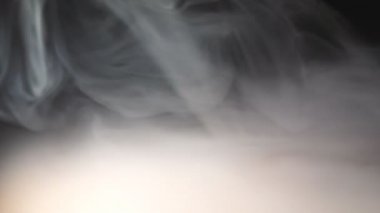 Masanın yüzeyinde yayılan vape gelen ağır beyaz duman düşük görünümü. Ahşap masa üzerinde kapsayan bir elektronik sigara veya nargile süt buhar Saf kulüp. Siyah arka plan. Yakın çekim