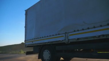 Yük römorklu kamyon yolda sürme ve gün batımında mal taşıma. Kamyon güzel doğa ortamı arasında kırsal üzerinden sürme. Ulaşım ve lojistik konsepti. Yavaş çekim Düşük görünüm