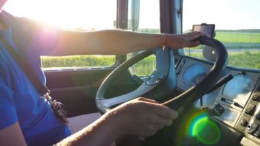 Tanınmaz adam kamyonetinin direksiyonuna oturan ve gün batımında kırsal üzerinden sürüş. Sürücü direksiyona ellerini tutarak ve hedefe sürme araba kontrol. Yavaş Mo yan görünüm