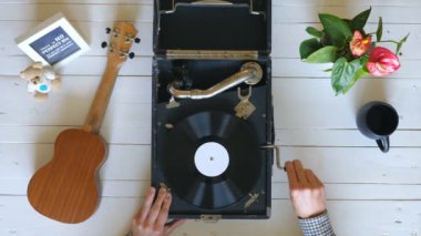 Beyaz masa arka planda vintage gramofon açma erkek elleri üzerinde üst görünümü. Klasik müziğin tadını çıkarmak için dönen siyah vinil kayıt üzerinde iğne ile kalem koyarak adam Kolu. Yavaş çekim Yakın çekim
