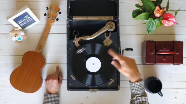 Beyaz masada vintage gramofon üzerinde dönen vinil kayıt yakın. Klasik müzikten zevk gösteren erkek ellerinin en iyi görünümü. Tanınmayan bir adam dinliyor ve kayıttan zevk alıyor. Yavaş çekim — Stok video