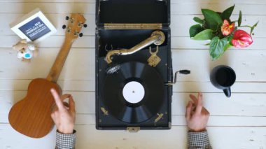 Beyaz masada vintage gramofon üzerinde dönen vinil kayıt yakın. Klasik müzikten zevk gösteren erkek ellerinin en iyi görünümü. Tanınmayan bir adam dinliyor ve kayıttan zevk alıyor. Yavaş çekim