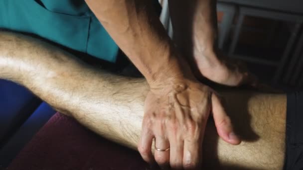살롱에서 젊은 스포츠맨의 힐링 문발을하고 있는 마사지스트의 맨 손탑. 전문 안마사 마사지 다리의 팔에서 마사지 테이블에 누워 운동 선수의 다리. 슬로우 모션 — 비디오