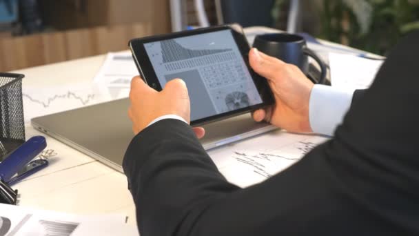 Mani maschili di un giovane imprenditore che sviluppa un progetto aziendale e analizza le informazioni statistiche su un tablet pc. Imprenditore di successo che lavora su un moderno dispositivo digitale in ufficio. Da vicino. — Video Stock