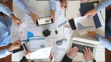 Ofiste kurumsal proje için strateji planlama iş adamlarının üst görünüm erkek ve kadın elleri. İş ekibi masada oturuyor ve finansal grafikleri kontrol ediyor. Masa başında belgeleri inceleyen iş arkadaşları