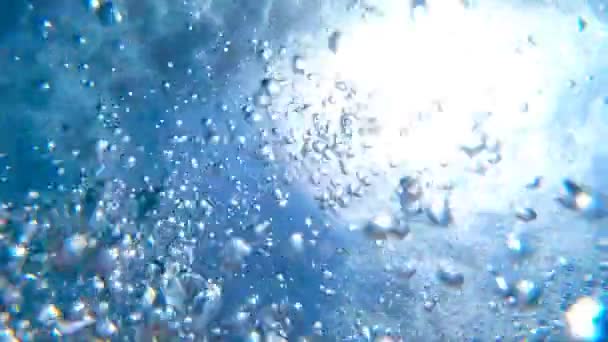 Hava kabarcıkları su yüzeyine kadar yüzen. Turkuaz saf denizde yükselen çok sayıda küçük hava kabarcıkları. Güneşli yaz gününde kristal berraklığında okyanus suyuna nüfuz eden ılık güneş ışığı. Yavaş çekim Yakın çekim — Stok video