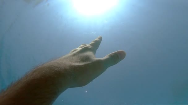 De mannelijke hand strekt zich uit van onder water tot zonnestralen. Arm vraagt om hulp en probeert naar de zon te reiken. Het standpunt van de mens die verdrinkt in de zee of oceaan en naar de oppervlakte drijft. Slow motion POV — Stockvideo