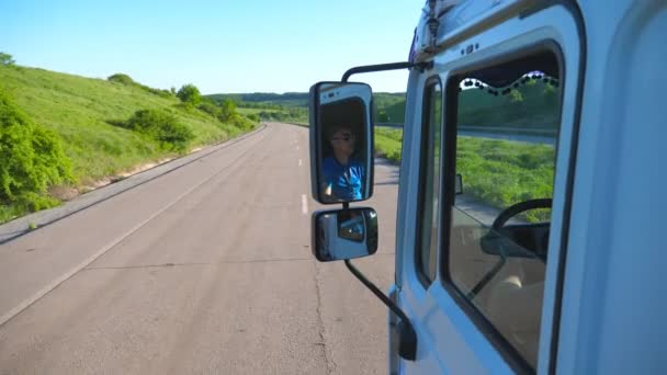Camionero en gafas de sol que reflejan en el espejo lateral del coche en movimiento. Hombre conduciendo camión a caballo a destino a través de carretera rural. Concepto de transporte de carga. Hermoso fondo. Lento mo Primer plano — Vídeos de Stock