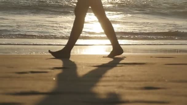 Ноги молодой женщины наступают на песок. Закрытие женских ног, идущих по золотому песку на пляже на фоне океанских волн. Босоногая девушка на берегу моря. Летние каникулы. Медленное движение — стоковое видео