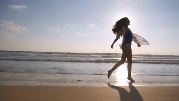 Suivez la femme heureuse en courant ou en faisant du jogging sur la plage près de l'océan. Jeune belle fille jouissant de la vie et s'amusant au bord de la mer. Vacances d'été ou vacances. Mouvement lent — Video