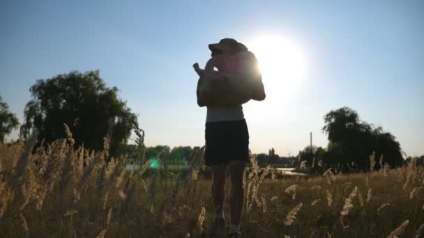 Joven llevando en las manos a su perro por campo. Jugando con labrador o golden retriever en la naturaleza. Amor y amistad con los animales domésticos. Primer plano: cámara lenta — Vídeos de Stock