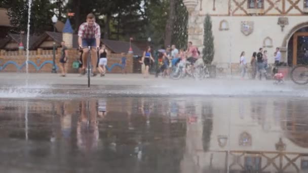 濡れた表面の自転車にブレーキをかける。公園でヴィンテージの自転車に乗っている若い男。アウトドアをサイクリングするスポーティ男。健康的な生活様式。フロントビューを閉じるスローモーション — ストック動画