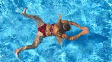 Kırmızı bikini Otel havuz rast yüzer tanınmaz halde güzel kız. Genç kadın güneşli günde Havzası masmavi suda yüzmek. Yaz tatili veya tatil kavramı. Üstten görünüm kapat