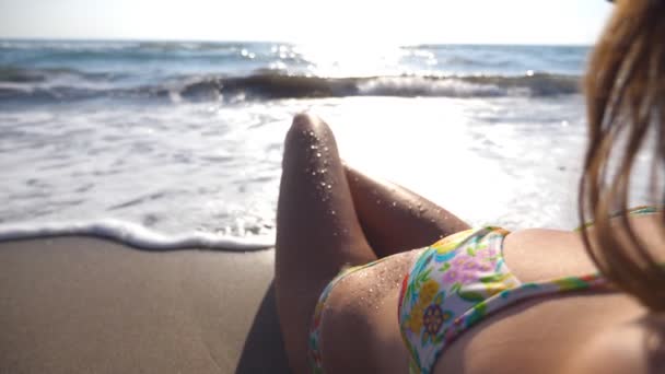 Chica sexy tumbada en la playa en las olas. Hermosa mujer joven relajándose en la orilla del mar durante el viaje de vacaciones de verano. Ondas oceánicas que se lavan sobre el cuerpo femenino bronceado. Cámara lenta Primer plano — Vídeos de Stock