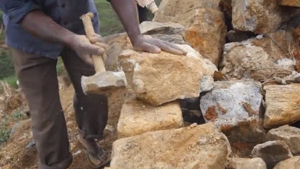 Side view of unrecognizable indian man cutting a block of granite with hammer in botanical garden. Adult human hitting stone with sledgehammer for construction flowerbed. Stonemason carving. Close up — Stock Video